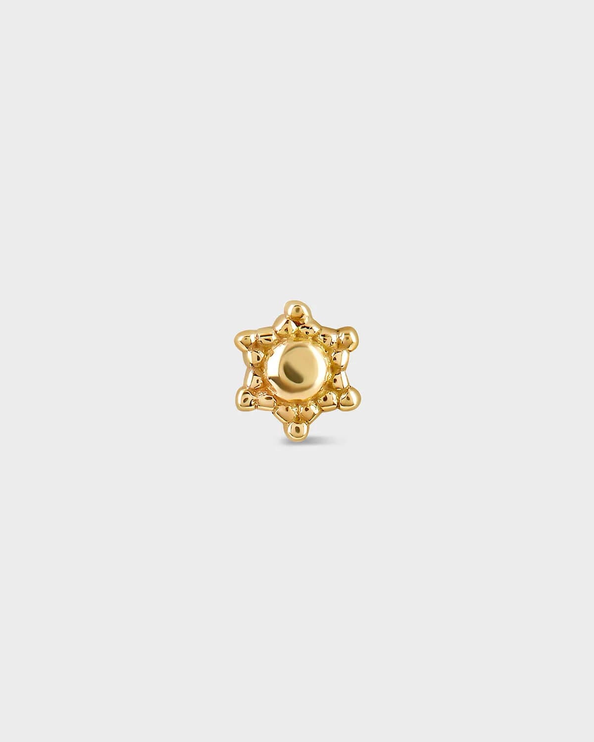 Gold star-shaped earring on a light gray background