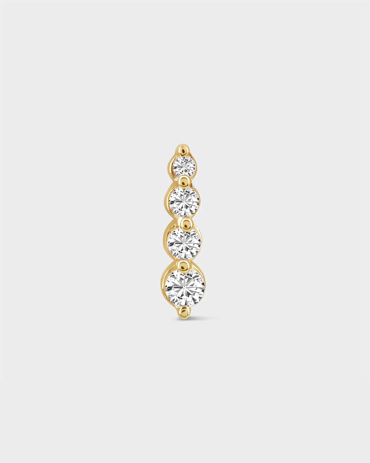 Gold earring with four clear gemstones on a light gray background