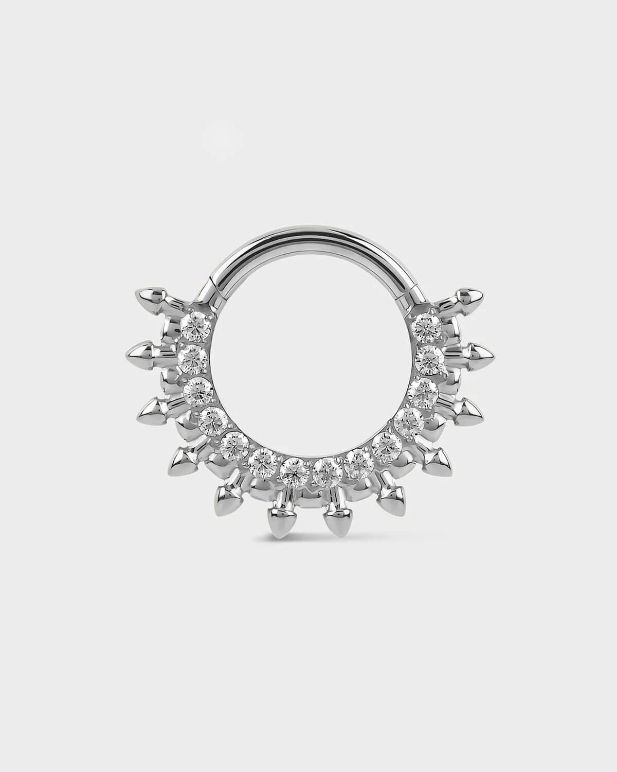 Polished titanium septum daith ring with diamond-like stones on a light gray background