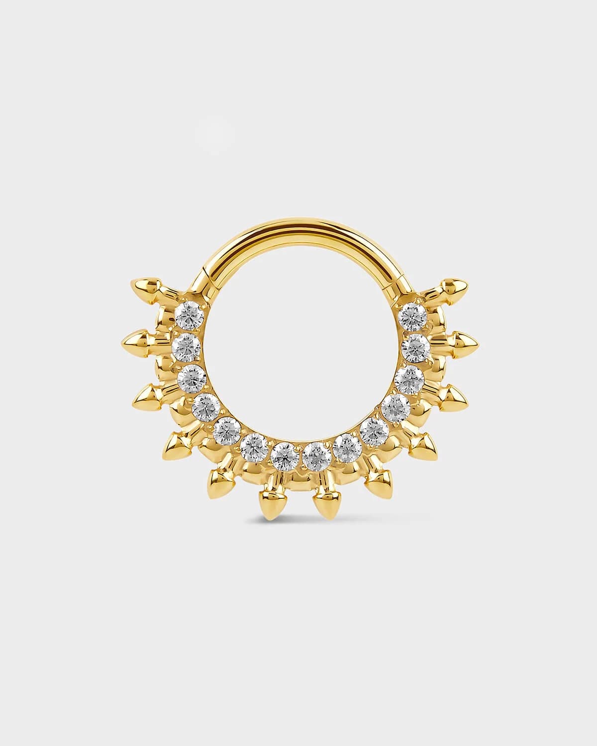 Gold septum daith ring with diamond-like stones on a light gray background