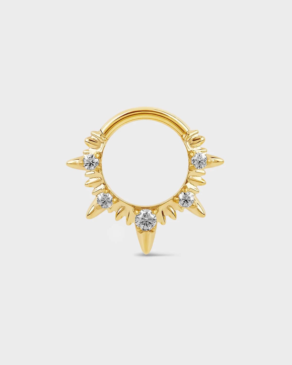 Gold septum ring with diamond-like stones on a light gray background