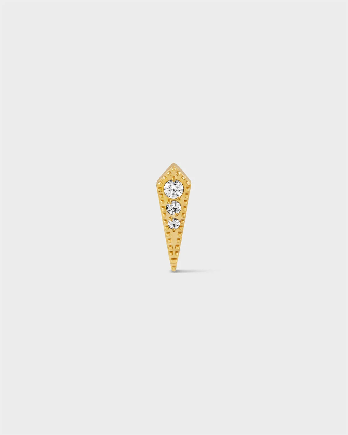 Gold titanium kite earring with triple gemstones and milgrain detail on a light grey background.
