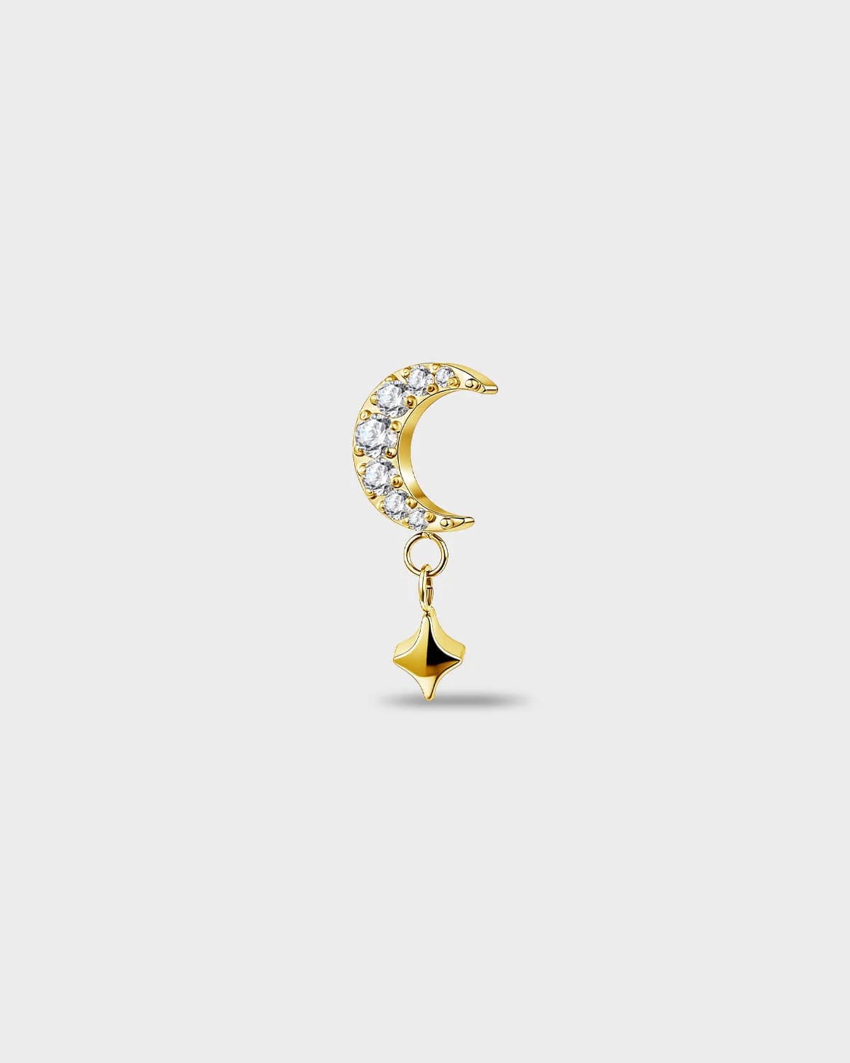 Gold titanium earring with a crescent shape set with clear round stones and a short dangle star detail on a light gray background.
