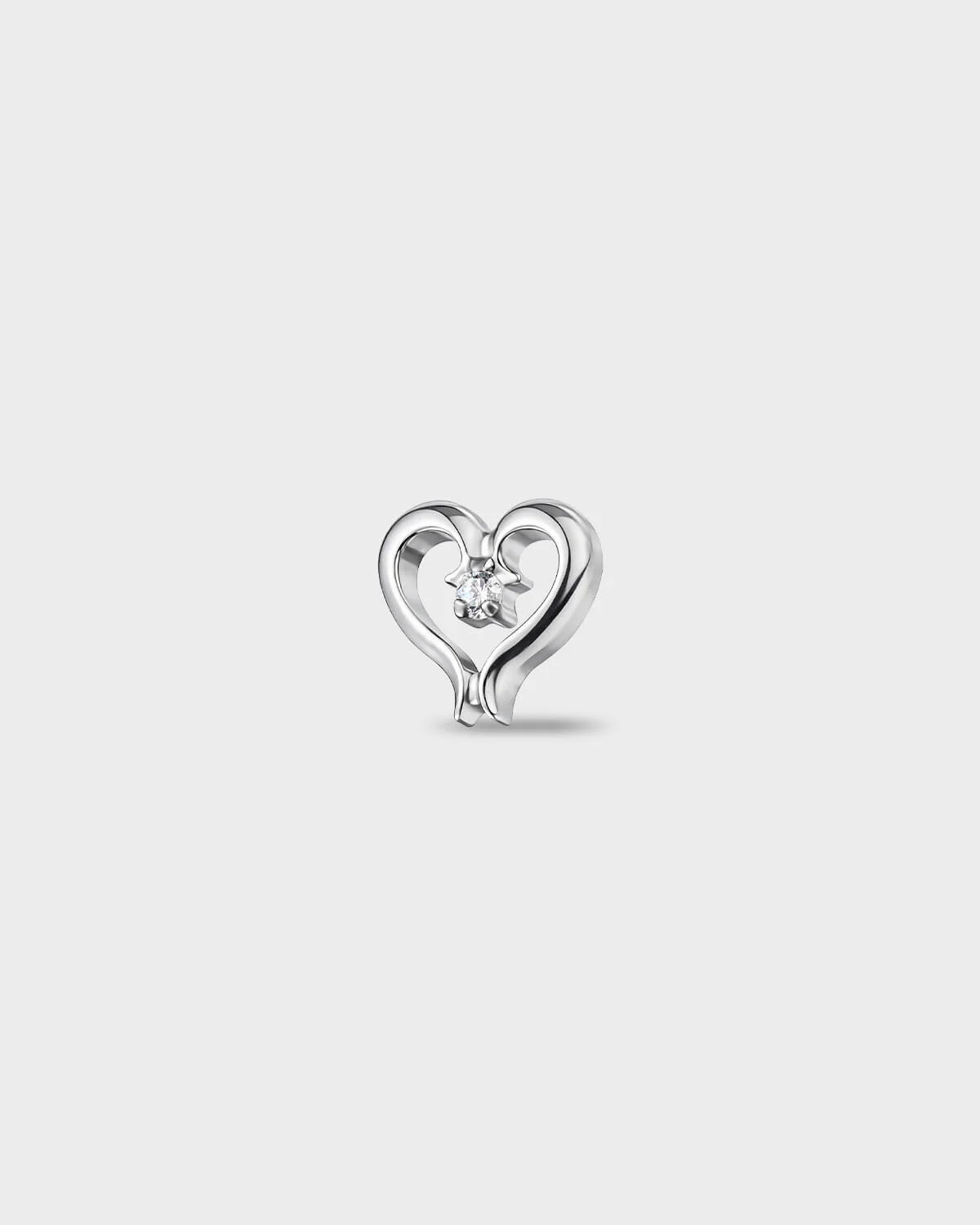 Polished titanium earring with an open heart shape and a single round-cut clear stone set at the centre, on a light gray background.