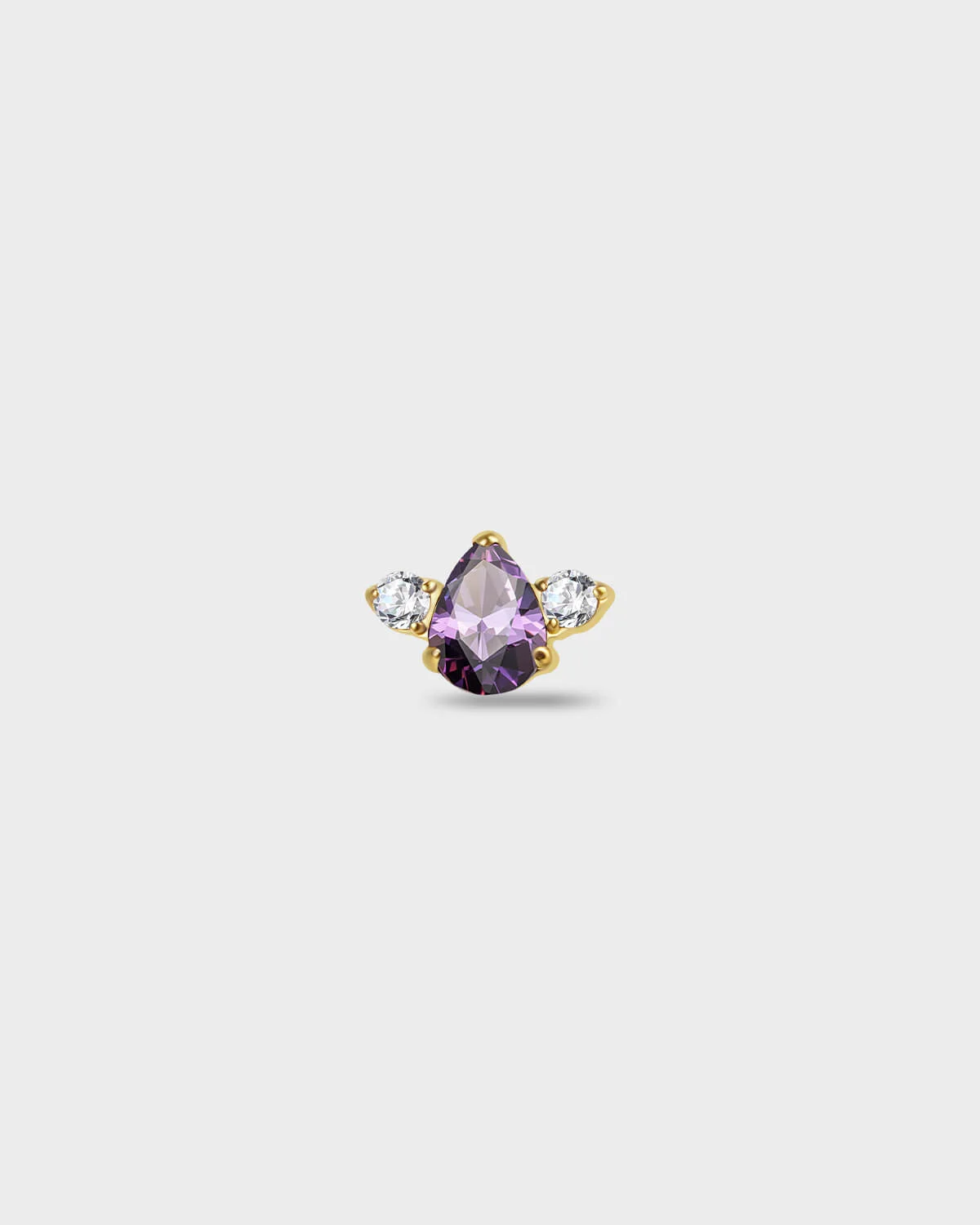 Gold titanium earring with a pear-cut purple stone set between two round-cut clear stones on a light gray background.